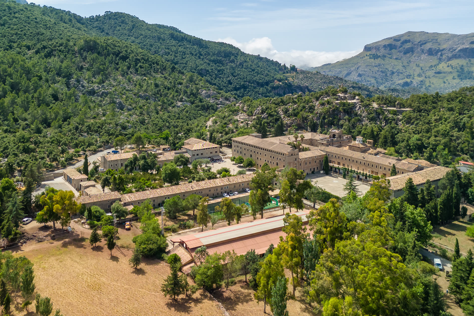 Luftbild einer großen Klosteranlage mit Innenhöfen zwischen bewaldeten Bergen Luftbild einer großen Klosteranlage mit Innenhöfen zwischen bewaldeten Bergen